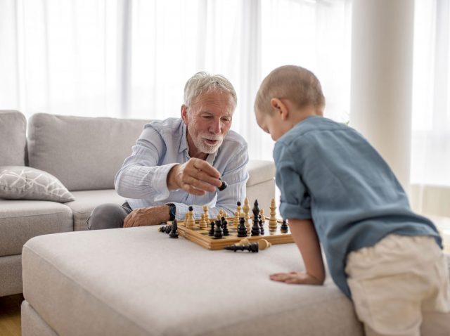 Adorable little boy playing chess with his grandfather Adorable little boy playing chess with his grandfather