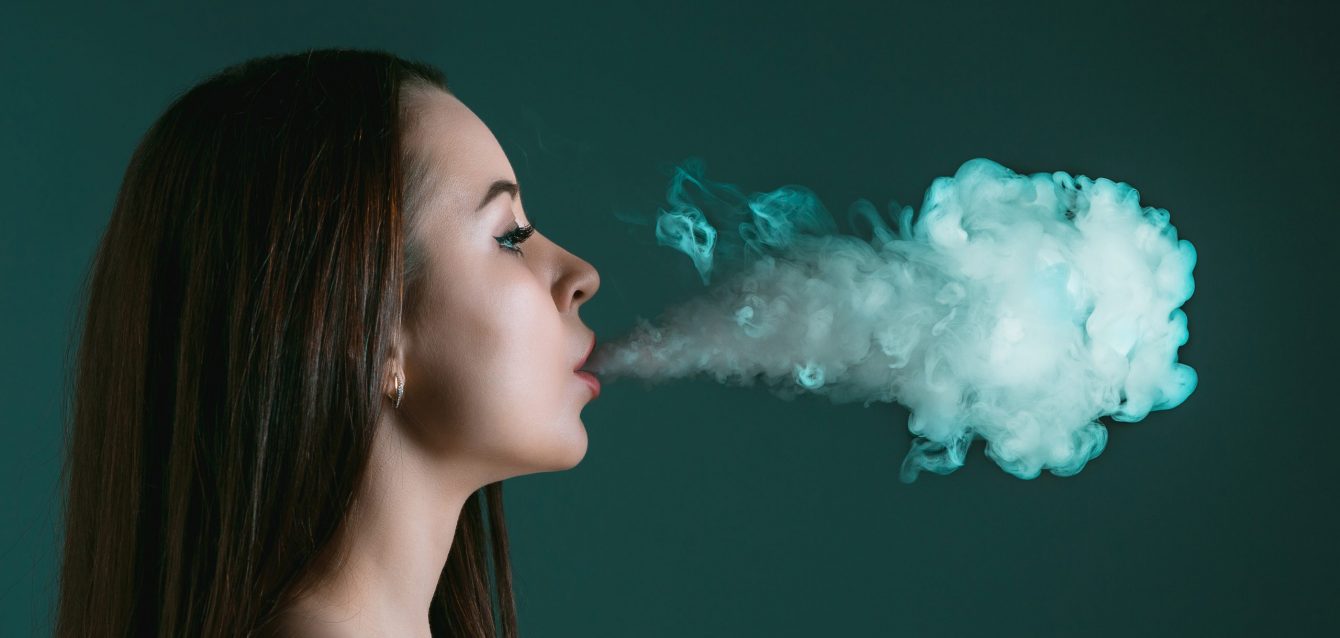 The face of vaping young woman at black studio The face of vaping young woman at black studio