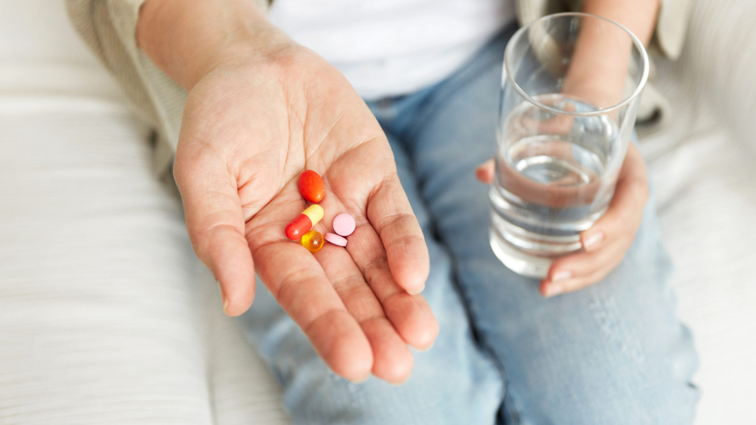 Píldoras, pastillas, vitaminas y drogas amontonadas en manos maduras, vista de cerca.