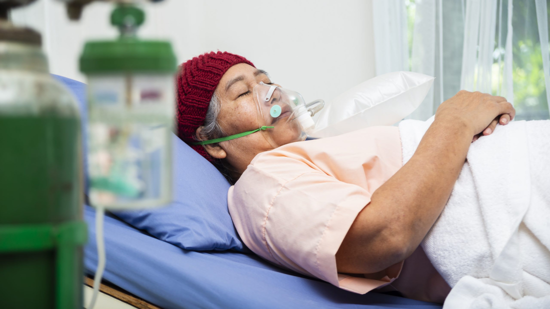 Anciana asiática con gorro de lana y máscara de oxígeno para respirar tumbada en la cama de un paciente, concepto médico y sanitario de mujer mayor.
