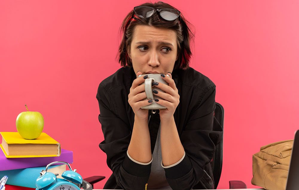 Estudiante preocupado y ansioso bebe una taza de café.
