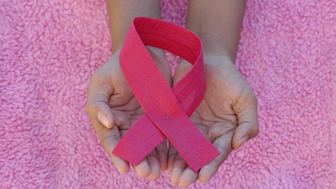 Breast Cancer Awareness Pink Ribbon in Hands Symbol