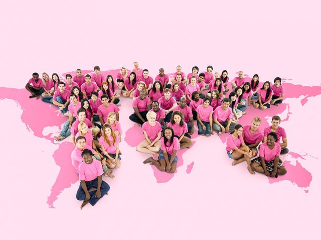 Grupo de mujeres y personas que apoyan la causa contra el cáncer de mama sentadas sobre una ilustración rosa de EE. UU.