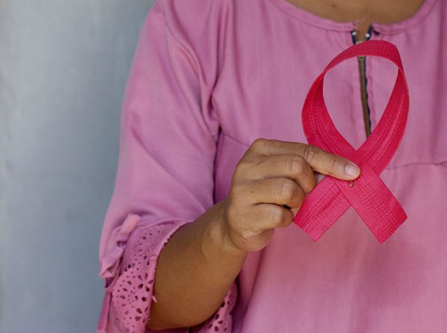 Mujeres con cáncer de mama sosteniendo un lazo rosa.