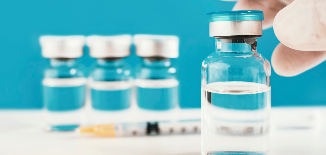 Viales de la vacuna contra el VRS con una jeringa sobre fondo azul.