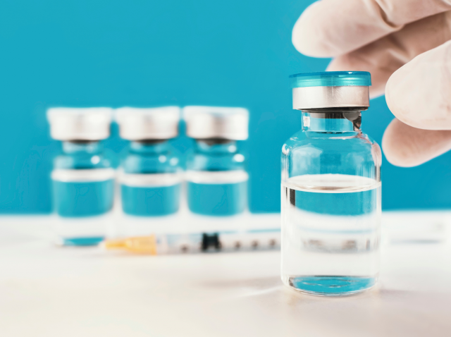 Viales de la vacuna contra el VRS con una jeringa sobre fondo azul.