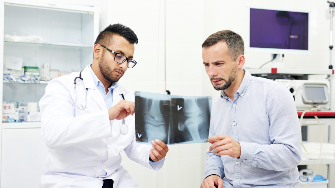 Radiologist and young man discussing x-ray images of joints