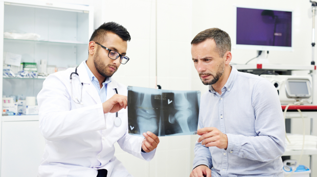 Radiologist and young man discussing x-ray images of joints