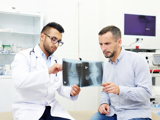 Radiologist and young man discussing x-ray images of joints