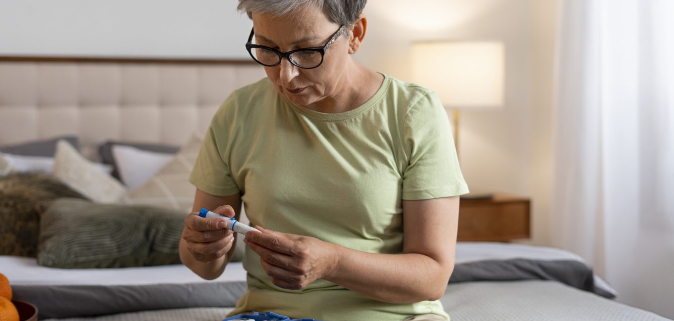 Mujer comprobando sus niveles de azúcar en sangre en casa como parte del control de trastornos metabólicos o lipídicos, como la hipertrigliceridemia.