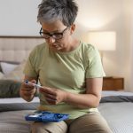 Mujer comprobando sus niveles de azúcar en sangre en casa como parte del control de trastornos metabólicos o lipídicos, como la hipertrigliceridemia.