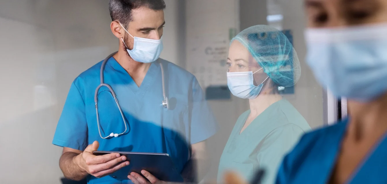 side-view-nurses-with-face-masks Sponsor recruitment support team of clinical research coordinators reviewing trial enrollment data at a community clinic research site.