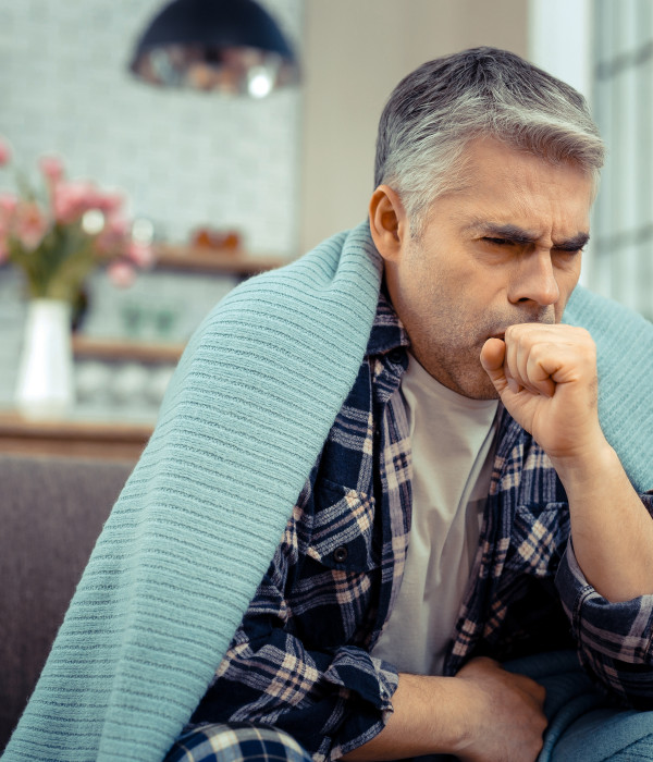 Suffering from cold. Unhappy cheerless man coughing into his hand while suffering from cold