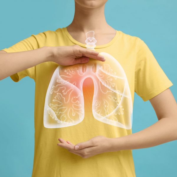 Mujer con las manos cerca del pecho y una ilustración de pulmones sobre fondo turquesa, primer plano.