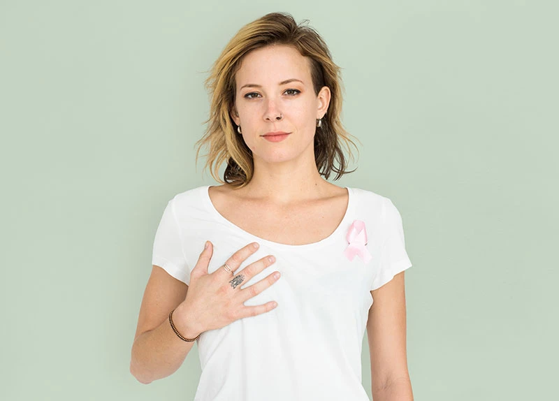 Una mujer con cáncer de mama se sujeta el pecho para someterse a pruebas