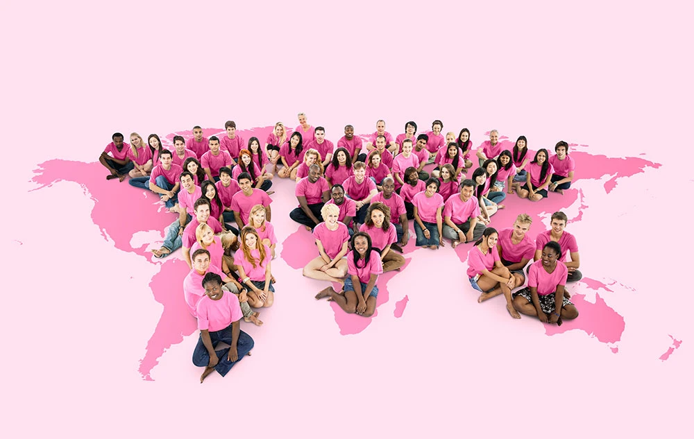 Grupo de mujeres y personas que apoyan la causa del cáncer de mama sentadas sobre una ilustración rosa de EE.UU.