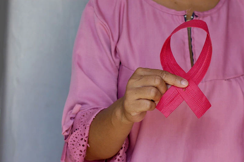 Mujeres con cáncer de mama sostienen un lazo rosa